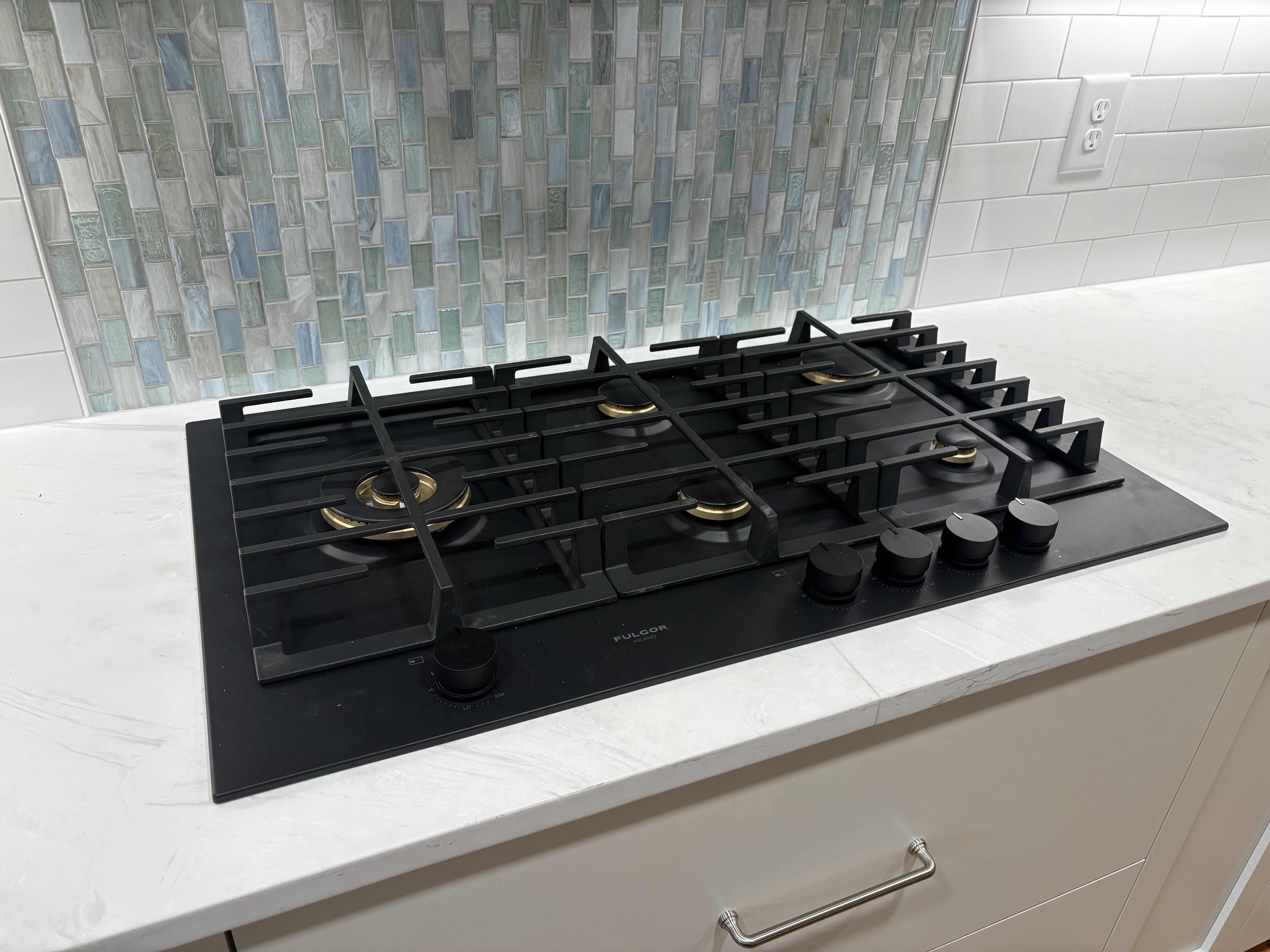 Five-burner gas cooktop installed against a tile backsplash